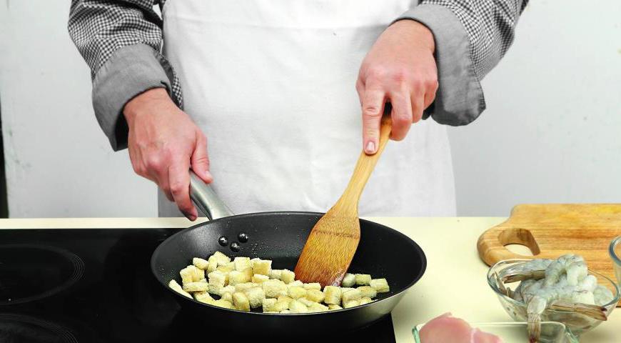 Снимите корку с хлеба и нарежьте мякоть небольшими кубиками (1,5–2 см). В сковороде разогрейте 45 мл оливкового масла и обжаривайте хлебные кубики, постоянно помешивая, до золотистого цвета (примерно 13 минут).