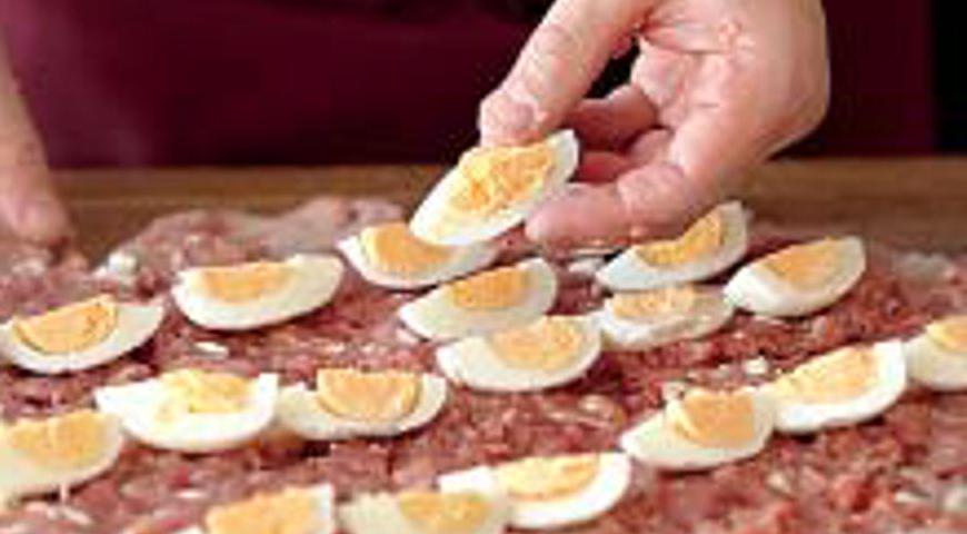 Выложите половину фарша на внутреннюю часть пласта мяса, затем распределите кусочки яиц и покройте второй частью фарша.