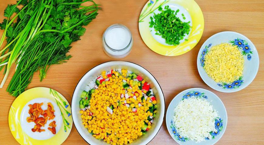 В глубокую миску добавьте рис, крабовые палочки, огурцы и кукурузу из банки (слить лишний сок).