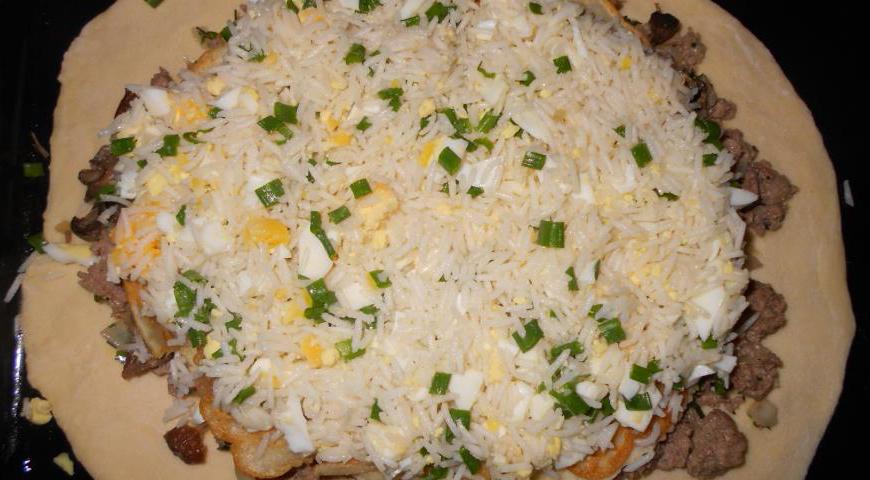 На нижний слой теста выложите мясную начинку. Сверху положите первый блин, далее — грибную начинку, второй блин, затем рисовую начинку и третий блин. Накройте вторым раскатанным пластом теста. Аккуратно защипните края, чтобы кулебяка была герметично закрыта. Сделайте несколько продольных надрезов сверху для выхода пара.