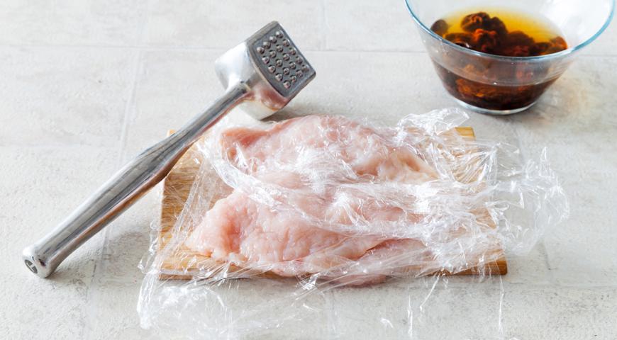 Возьмите куриные грудки и сделайте аккуратный продольный надрез, не доходя до конца. Разверните их, как книгу, и отбейте с обеих сторон между пищевой пленкой до получения равномерного слоя толщиной около 0,5 см.
