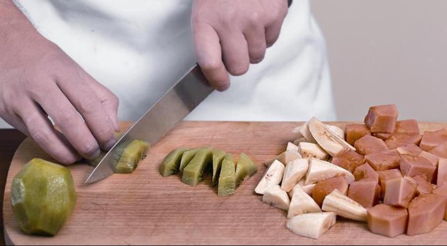 Нарежьте все фрукты аккуратными кусочками разной формы для эстетичного внешнего вида. Переложите их в глубокую ёмкость, залейте охлаждённым сиропом и оставьте настояться минимум на 1 час. Для более насыщенного вкуса поставьте в холодильник на 24 часа перед подачей.