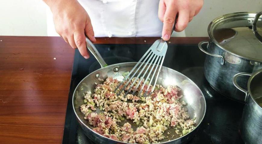 На сковороде разогрейте оливковое масло и обжарьте лук с чесноком до золотистого цвета. Добавьте фарш и жарьте, постоянно помешивая, около 6 минут. Затем вмешайте петрушку и добавьте помидоры, перемешав все ингредиенты. Посолите соус, добавьте орегано и продолжайте готовить еще 5–6 минут.