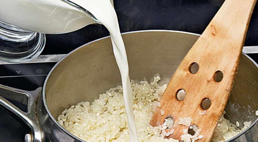 В глубокой кастрюле с толстым дном разогрейте топленое масло, всыпьте рис и обжаривайте на медленном огне до полупрозрачности зернышек, около 3-4 минут. В отдельной кастрюле смешайте молоко, разрезанный вдоль стручок ванили, сахар и щепотку соли; доведите до кипения и поддерживайте тепловой режим.