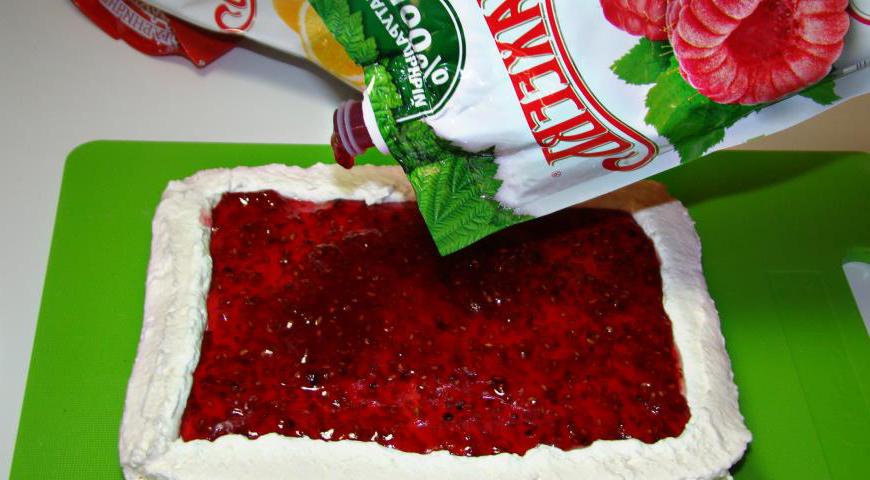 На первый корж нанесите крем, сверху распределите малиновый джем.