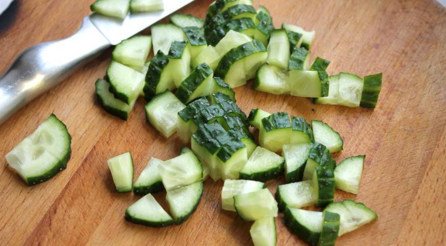 Свежие огурцы промойте, обсушите и нарежьте кубиками.