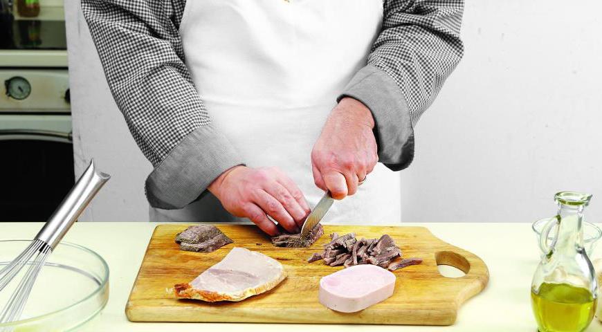 Нарежьте мясное ассорти тонкой соломкой. Красный лук очистите и нарежьте полукольцами. Маринованные огурцы мелко порубите. Помидоры черри разрежьте на две части.
