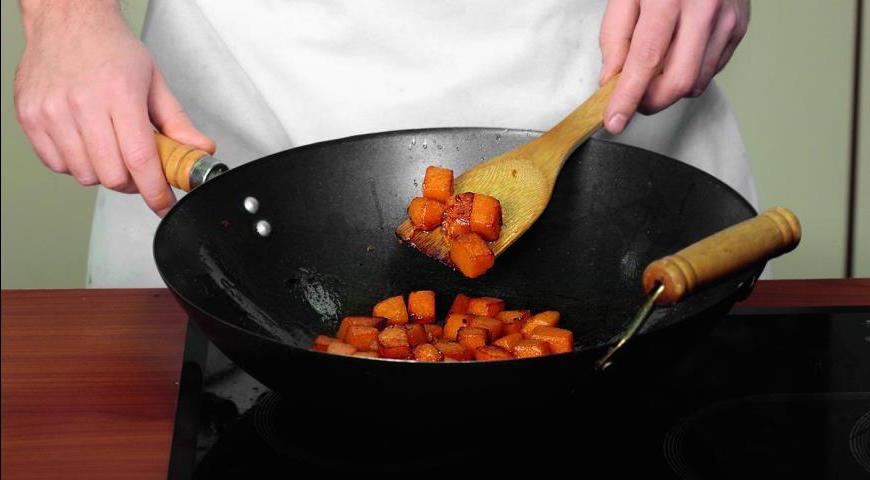 Нарежьте тыкву небольшими кубиками. Растопите оставшееся масло в глубокой сковороде или воке. Добавьте тыкву, приправьте сахаром и солью, жарьте до готовности 9–11 минут.