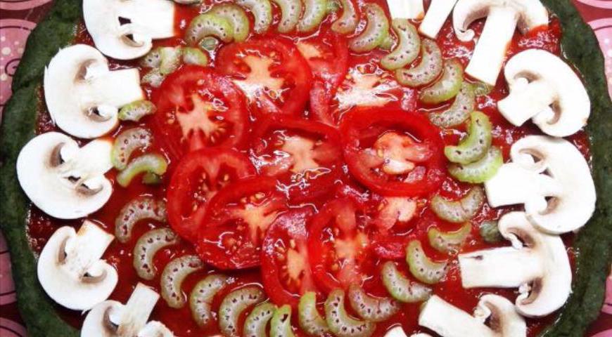 Аккуратно выложите на пиццу кружочки помидоров, порезанные пластинками шампиноны и нарезанный стебель сельдерея.