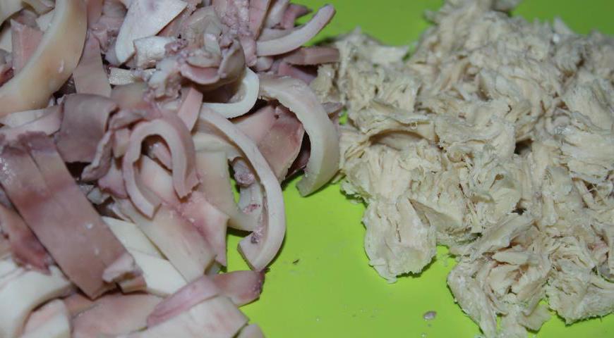 Отварное куриное филе нарежьте небольшими кубиками. Кальмары, предварительно отваренные, порежьте тонкой соломкой.