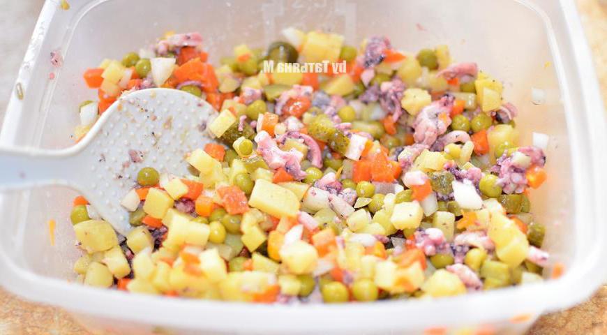 Картофель, морковь и репчатый лук нарежьте одинаковыми кубиками и хорошо перемешайте. Добавьте зеленый горошек, порезанные корнишоны и кусочки осьминога. Аккуратно смешайте.