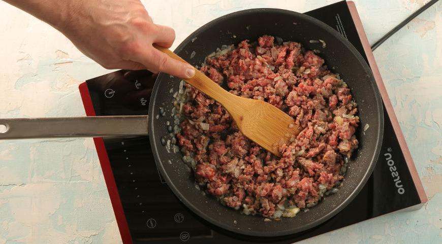 На сковороде разогрейте масло, добавьте измельченный лук и чеснок, обжаривайте до золотистого цвета. Затем добавьте говяжий фарш, перемешайте и готовьте, разбивая комочки, около 10 минут, пока он не станет румяным.