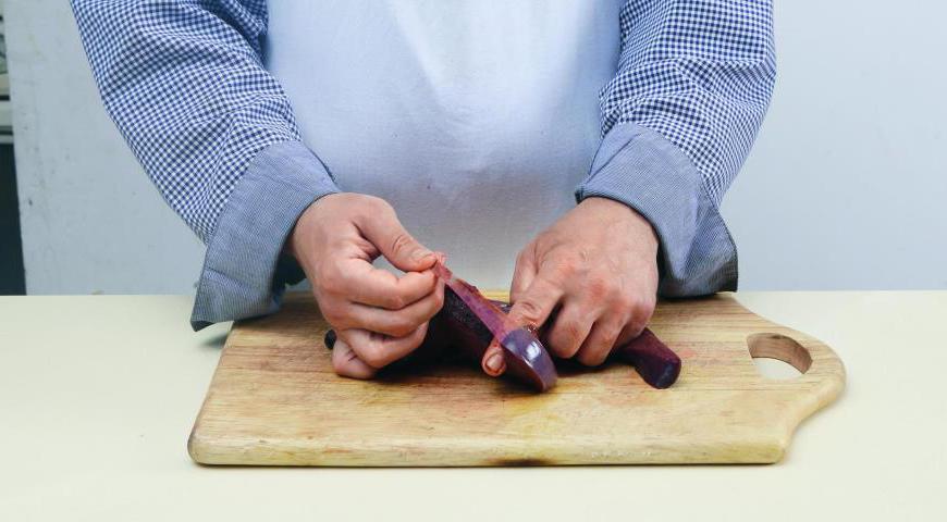 Положите печенку на ровную поверхность и аккуратно отделите пленку с помощью ножа. Далее продолжайте очищать руками, если пленка легко отходит. Также уберите крупные протоки с помощью острого ножа.
