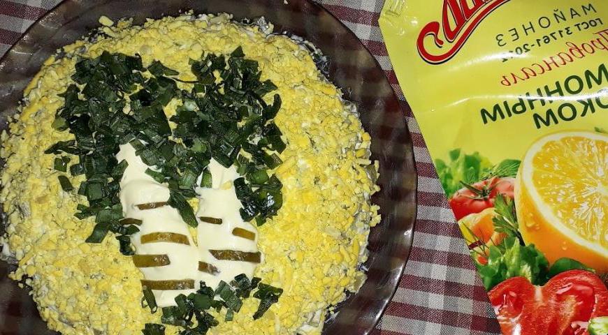 Пятый и финальный слой — желтки, натертые на крупной терке. Украшаем салат в виде березы: сделайте полосы из майонеза — это ствол, а пятна можно выполнить из мелко нарезанного огурца или маслин. Листву добавьте из мелко нарезанного зеленого лука.