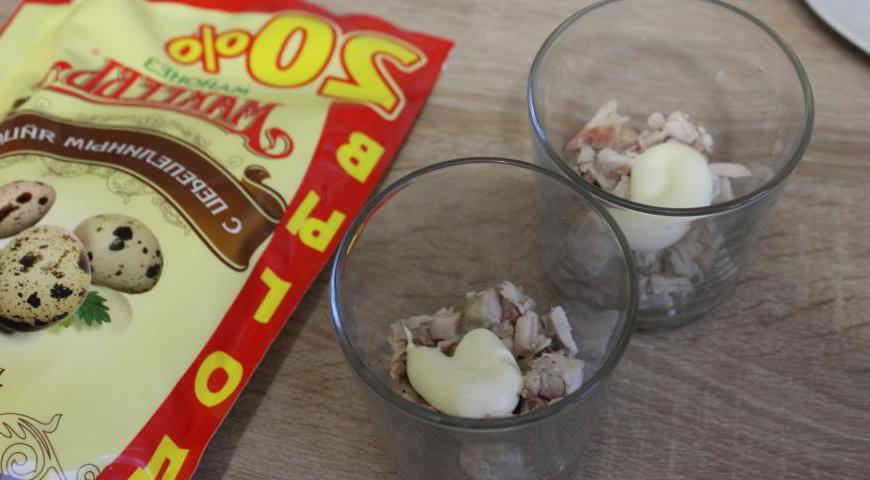 На дно прозрачных стаканов выложить подготовленную курицу и немного майонеза.