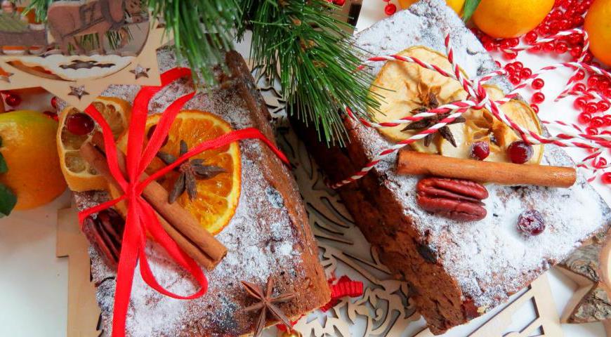 Форму для выпечки смажьте маслом, выложите тесто и аккуратно распределите, слегка примяв руками. Переверните форму на противень с пергаментом и отправьте в разогретую духовку до 180°C. Выпекайте около 80 минут. Готовность проверьте зубочисткой. После остывания посыпьте штоллен сахарной пудрой.