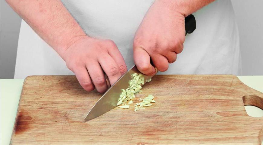 Раздавите, очистите и измельчите чеснок. Отделите листья петрушки от стеблей и порубите их вместе с чесноком как можно мельче.