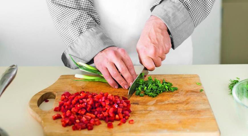 Очистите сладкий перец и нарежьте его мелкими кубиками. Зеленый лук нарежьте очень тонко. Добавьте перец и лук к остывшей пасте с кукурузой.