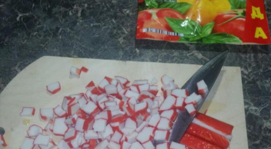 Крабовые палочки нарежьте мелкими кубиками, чтобы они равномерно распределились по салату.