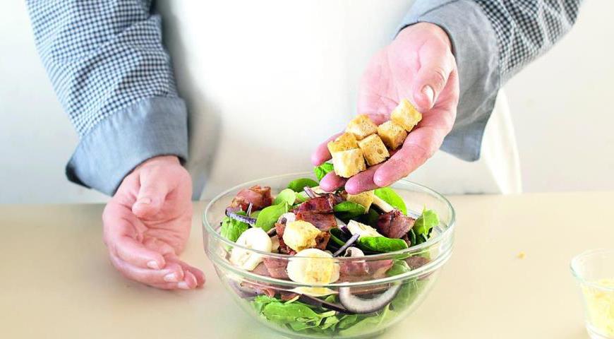 Смешайте в салатнице шпинат, грибы, яйца, гренки и кусочки бекона. Полейте салат горячей заправкой, посыпьте тертым сыром, аккуратно перемешайте и сразу же подавайте к столу.