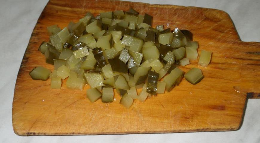 Маринованный огурец также нарежьте мелкими кусочками. Это добавит сочности и легкой кислинки блюду.
