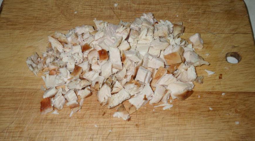 Запеченную куриную грудку нарежьте мелким кубиком. Так она лучше смешается с другими ингредиентами.