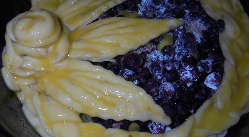 К чернике добавьте тростниковый сахар и кукурузный крахмал, перемешайте и выложите поверх творожного слоя. Сверху красиво расположите подготовленные украшения из теста. Смажьте их яичным желтком и посыпьте тростниковым сахаром для золотистого блеска и хрустящей корочки.