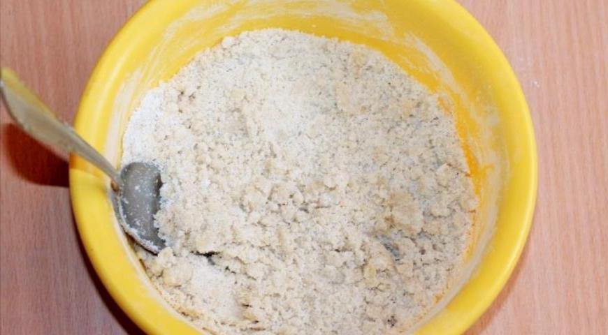 Добавьте мягкое сливочное масло к сухой смеси и аккуратно перетрите его с мукой до получения крошки.