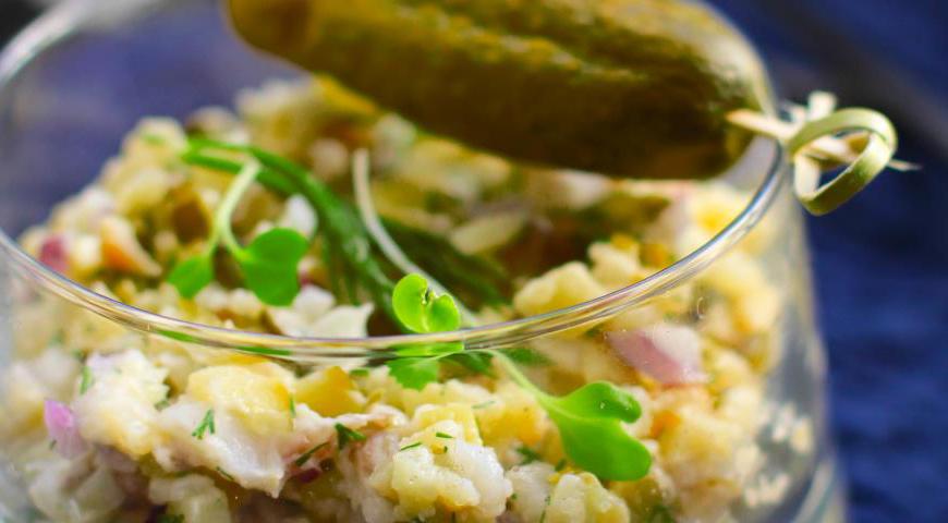 Вначале смешайте нарезанный картофель с оливковым маслом, чтобы он покрылся плёнкой и не слипался. Затем добавьте все ингредиенты: рыбу, корнишоны, лук и укроп. Введите майонез и слегка поперчите. При необходимости досолите — но учтите, что копчёная рыба, корнишоны и майонез уже содержат соль.