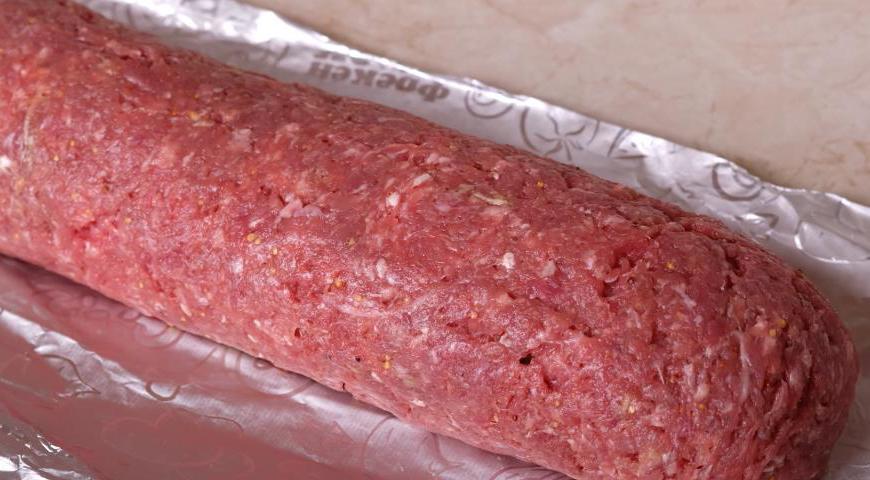Аккуратно сверните фарш вместе с начинкой в рулет, стараясь не повредить форму.