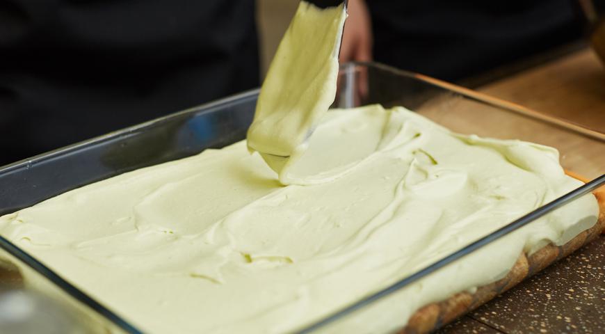 Приготовьте крепкий кофейный напиток Moccona Vanilla и добавьте в него ликер Амаретто. Остудите немного. Печенье савоярди быстро окуните в остывший кофе и выложите на дно формы. Сверху распределите слой крема. Повторите ещё один слой печенья и завершите кремовым верхом.