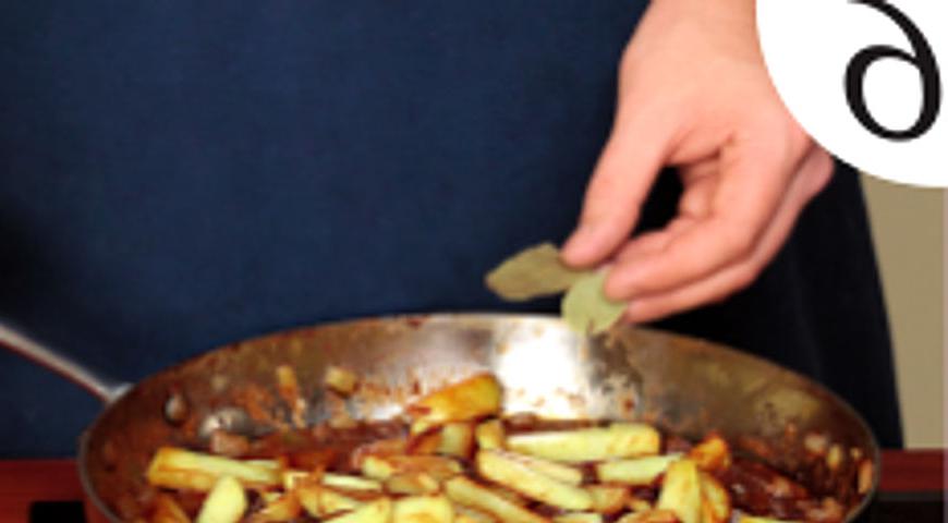 Добавьте обжаренный картофель в общую сковороду с мясом, положите лавровый лист и аккуратно перемешайте. Тушьте еще 7 минут, затем добавьте натертый чеснок, перемешайте и сразу же подавайте к столу.