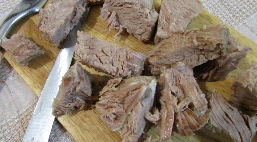 Хорошо промойте мясо и залейте его холодной водой. Поставьте кастрюлю на средний огонь, доведите до кипения и варите, снимая пену, пока мясо не будет почти готово. Затем выньте мясо из бульона, дайте немного остыть и нарежьте небольшими кусочками. Процедите бульон.