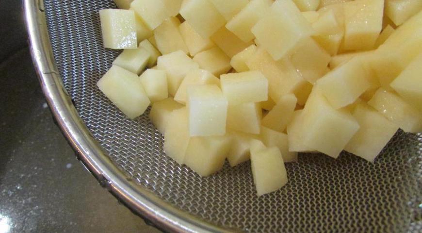 Очистите картофель, нарежьте его небольшими кубиками и отправьте в кипящий бульон. Варите около 10 минут, до полуготовности.