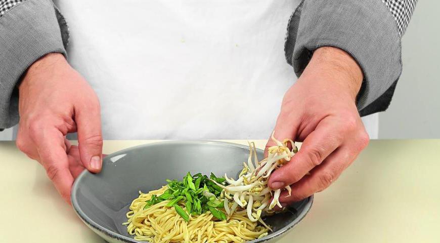 На лапшу положите зеленый лук, рядом добавьте ростки и кусочки курицы. Залейте кипящим бульоном. Сверху выложите разрезанные пополам маринованные яйца и сразу подавайте к столу.