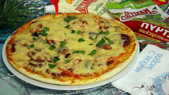Вкусная пицца с копченой колбасой, маринованными огурцами и ароматными травами