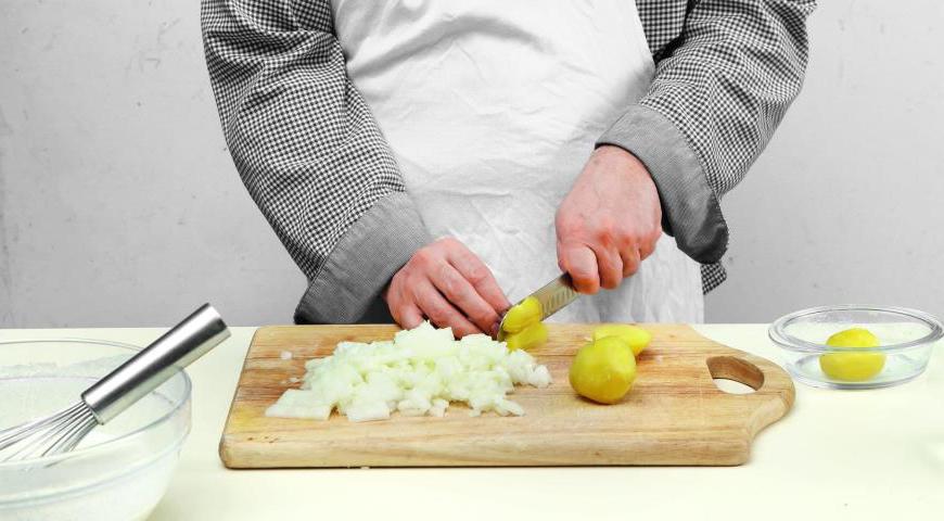 Для приготовления припека очистите отварной картофель и нарежьте его кубиками размером около 8 мм. Аналогично подготовьте луковицу, нарезав ее небольшими кусочками. Разогрейте сковороду с маслом и обжарьте лук до золотистого цвета в течение 12 минут, затем переложите его в отдельную емкость.