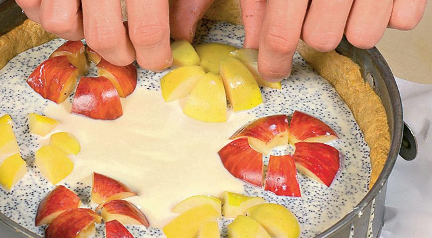 Нарежьте яблоки дольками, уложите их в форму и выпекайте чизкейк в течение 55 минут при температуре 185 °С.