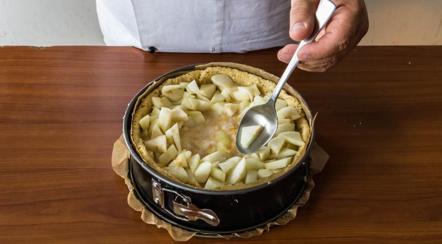 На подготовленное тесто выложите яблочное пюре, смешанное с хлебными крошками. Разместите поверх нарезанные яблочные дольки. Выпекайте при температуре 210 °С в течение 13-16 минут, затем дополнительно подрумяньте под грилем 3-4 минуты.