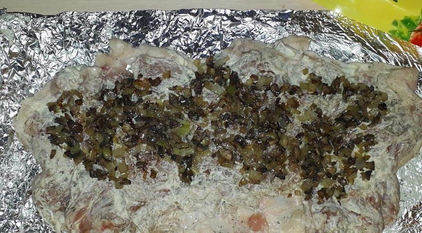 Ближе к одному краю мяса выложите обжаренные грибы с луком.