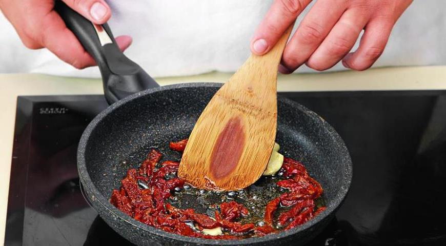 Нарежьте вяленые помидоры небольшими кусочками. Раздавите и очистите зубчик чеснока. Поместите их в маленькую сковороду, добавьте оливковое масло и прогрейте на среднем огне. После прогревания удалите чеснок.