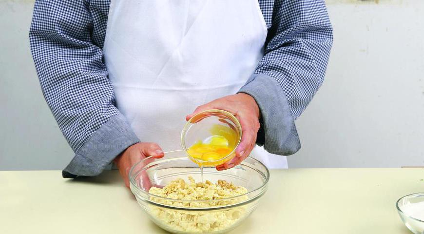 Подготовьте духовку (175 °C). В глубокую миску просейте муку, добавьте сахар, соль и холодное масло. Перетрите все руками до состояния крупной крошки, затем введите желтки и замесите эластичное тесто.