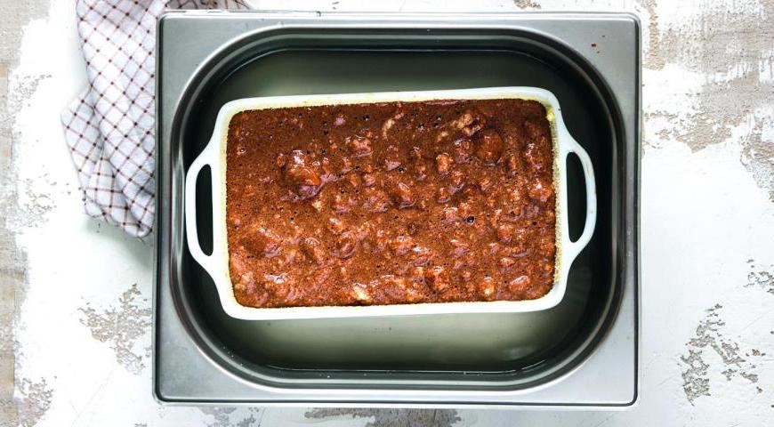 Форму для запекания смажьте сливочным маслом и обсыпьте толчеными сухарями. Выложите тесто, установите форму в более крупную ёмкость и наполните её горячей водой до середины бортиков маленькой формы. Отправьте в духовку на 30 минут. Готовое блюдо подавайте прямо в форме, горячим.