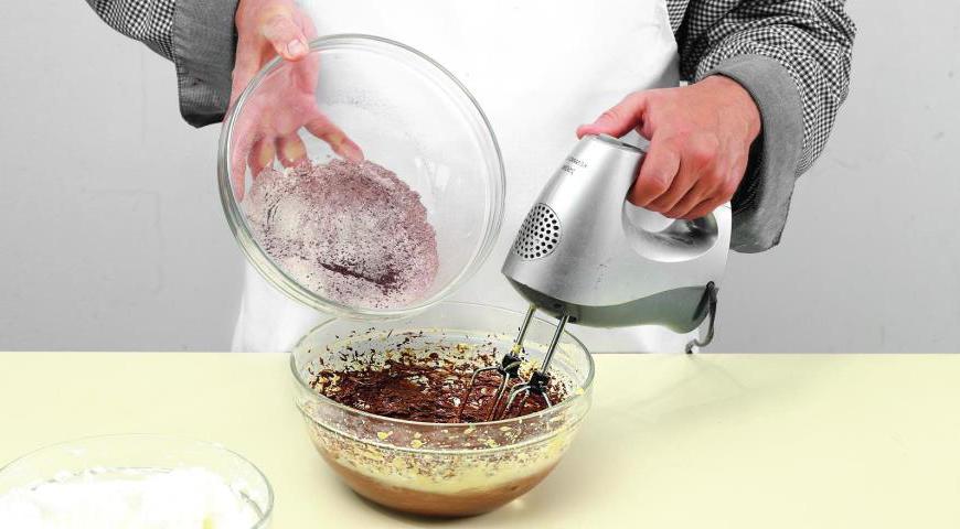 Разогрейте духовку до 180 °C. Начните взбивать мягкое масло миксером, постепенно добавляя сахарную пудру. Затем, продолжая взбивать, добавляйте желтки и растопленный шоколад чередуя. После этого начинайте понемногу добавлять смесь из муки и какао.