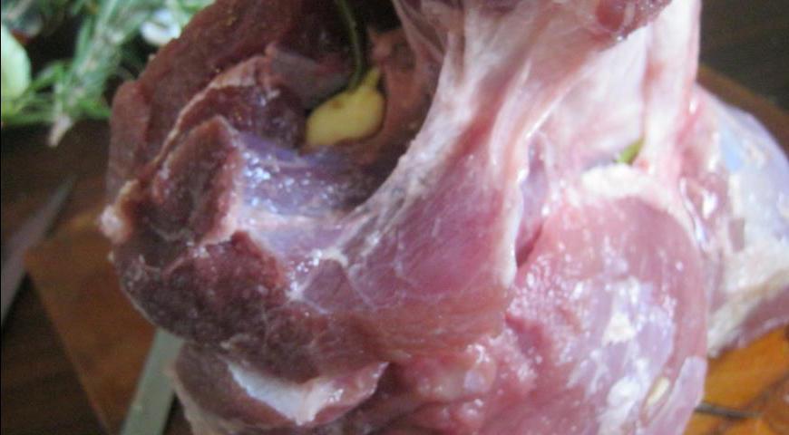 Аккуратно сделайте глубокие надрезы в мясе и вложите внутрь немного соли, розмарина и чеснока.