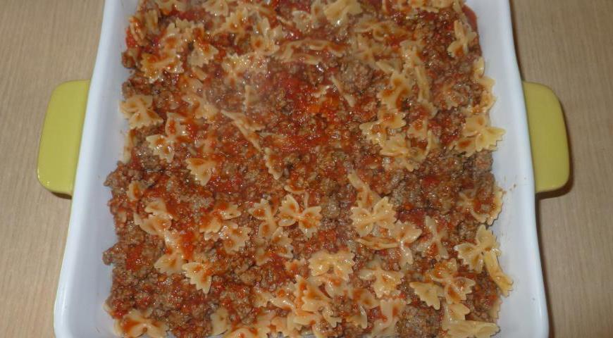 Добавьте отваренные макароны в сковороду к мясу, аккуратно перемешайте до равномерного распределения ингредиентов.